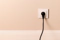 Electrical outlet with plug on beige wall Royalty Free Stock Photo