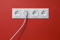 Electrical outlets, cable and electric plug on red