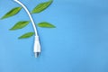 Electrical plug with growing green leaves in blue background. Save electricity and alternative energy concept. Royalty Free Stock Photo