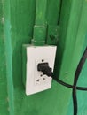 Electrical plug and socket on green wall, closeup of photo Royalty Free Stock Photo