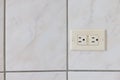 Electrical plug type B on the tiled wall in a bathroom. Royalty Free Stock Photo