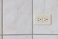 Electrical plug type B on the tiled wall in a bathroom.