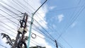 Electrical poles full of tangled cables under the blue sky Royalty Free Stock Photo