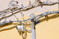 Electrical power cables and telephone cables against an old brick and plaster wall placed in a confused and twisted way Royalty Free Stock Photo