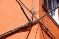 Electrical power cables, telephone cables, and metal water pipes in front of an old building facade Royalty Free Stock Photo