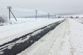 Electrical power lines with hoarfrost on the wooden electric poles on countryside in the winter and winter road Royalty Free Stock Photo