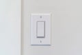 Electrical rocker light switch with flat broad lever on white interior wall