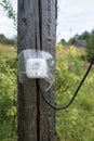 Electrical socket with a wire, protected from moisture by a transparent visor, is attached to an old wooden post Royalty Free Stock Photo