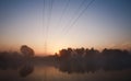 Electrical steel pylon and cable in haze at sunset in forest Royalty Free Stock Photo