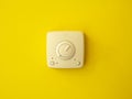 An electrical switch in the center on a yellow wall. Frontal view. Royalty Free Stock Photo