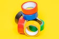 Electrical tapes isolated. Close-up of a set of colorful rolls of insulation adhesive tapes on a yellow background. Macro