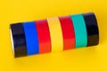 Electrical tapes isolated. Close-up of a set of colorful rolls of insulation adhesive tapes on a yellow background. Macro