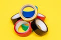 Electrical tapes isolated. Close-up of a set of colorful rolls of insulation adhesive tapes on a yellow background. Macro