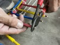 An electrical technician cutting insulated wire using cable cutter. Royalty Free Stock Photo