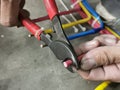 An electrical technician cutting insulated wire using cable cutter. Royalty Free Stock Photo