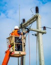 An electrical worker is elevated in a cherry picker, performing maintenance on a utility pole Royalty Free Stock Photo