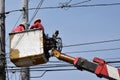 Electrical Workers On Telehandler With Bucket installing High tension wires on tall concrete post. Underside view low angle