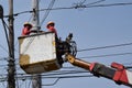 Electrical Workers On Telehandler With Bucket installing High tension wires on tall concrete post. Underside view low angle Royalty Free Stock Photo