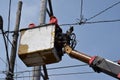 Electrical Workers On Telehandler With Bucket installing High tension wires on tall concrete post. Underside view low angle Royalty Free Stock Photo