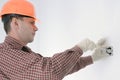 Electrician in helmet installing electrical box in appartment