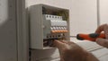 Electrician assembles electrical panel. Close up of a man hands tightening screw with a screwdriver in a switchboard Royalty Free Stock Photo