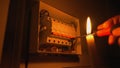 Electrician assembles electrical panel in dark by light of burning candle. Close up of a mans hands tightening a screw Royalty Free Stock Photo