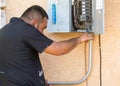 Electrician attaching metal conduit to fuse box