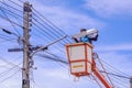Electrician in bucket boom truck is repairing street light pole against blue sky background Royalty Free Stock Photo