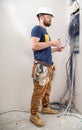 Electrician Builder at work, examines the cable connection in the electrical line in the fuselage of an industrial switchboard.