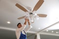 Electrician changing light bulb in ceiling fan indoors Royalty Free Stock Photo