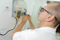 Electrician checking socket voltage using multimeter in wall Royalty Free Stock Photo