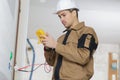 Electrician checking socket voltage using multimeter in wall fixture Royalty Free Stock Photo