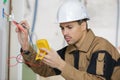 Electrician checking socket voltage using multimeter in wall fixture Royalty Free Stock Photo