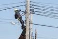 Electrician connects wires on a pole against blue sky