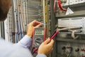 Electrician engineer with multimeter tests electrical control panel of automation equipment. Specialist in the Controller cabinet. Royalty Free Stock Photo