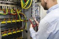 Electrician engineer testing cabling connection of high voltage power electric line in industrial distribution fuse board
