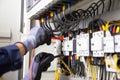 Electrician engineer tests electrical installations and wires on relay protection system. Adjustment of scheme of automation and Royalty Free Stock Photo