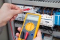 Electrician examining fusebox with resistance tester