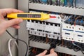 Electrician examining fusebox with voltage tester Royalty Free Stock Photo