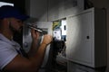 Electrician with flashlight fixing electric panel Royalty Free Stock Photo