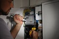 Electrician with flashlight fixing electric panel indoors