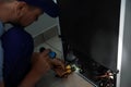 Electrician with flashlight fixing refrigerator indoors