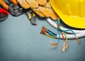 Electrician gloves and tools on wooden background Royalty Free Stock Photo