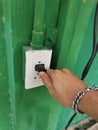 electrician hand turning off the light switch on the green wall. Royalty Free Stock Photo