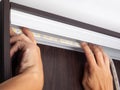 Electrician hands install LED strip lighting in the niche of the cabinet to illuminate the wardrobe