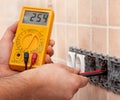 Electrician hands measuring voltage in electrical wall socket wi Royalty Free Stock Photo