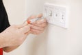 Electrician hands tighten electrical wires in wall fixture or socket using a screw driver - closeup. Installing electrical outlet Royalty Free Stock Photo