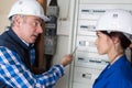 Electrician and female apprentice checking electrical outlet