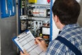 Electrician Holding Clipboard While Examining Fusebox