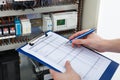 Electrician holding clipboard while examining fusebox Royalty Free Stock Photo